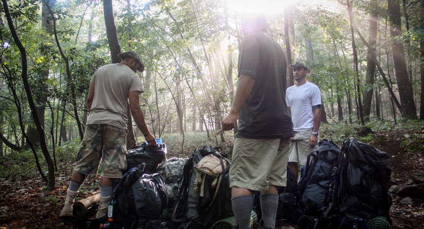 a group of veterans assemble their packs on an outward bound expedition